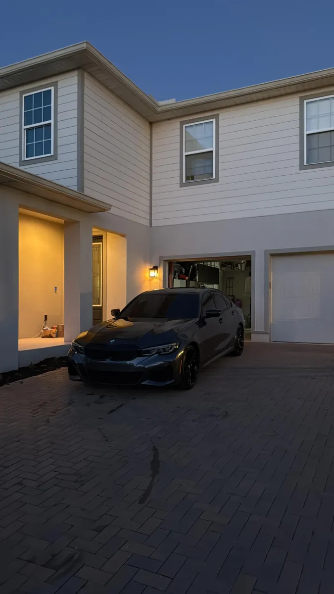 Dark BMW sedan in a driveway at dusk after a mobile detail