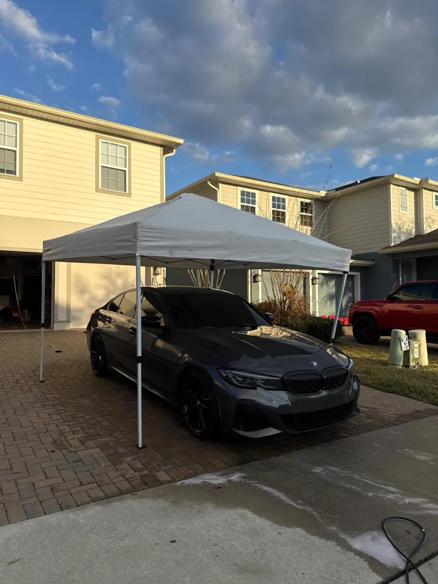 Dark BMW sedan under the Shine Craft Auto Spa mobile detailing canopy
